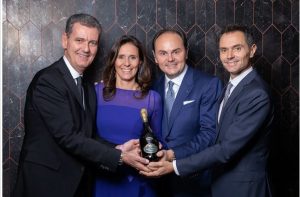Marcello, Matteo, Camilla und Alessandro Lunelli mit einer Flasche Wein in der Hand