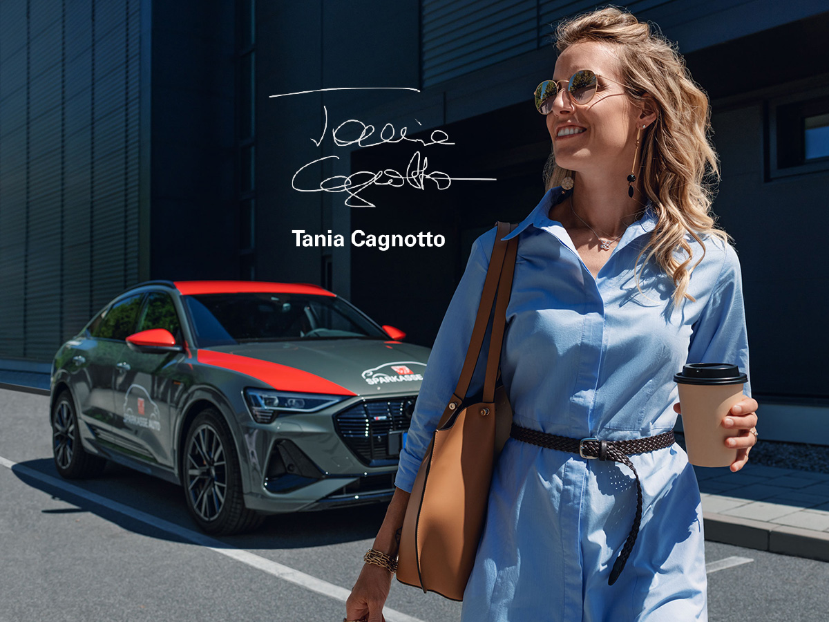 Tania Cagnotto mit einem Audi der Sparkasse Auto im Hintergrund und ihrer Unterschrift in der Mitte