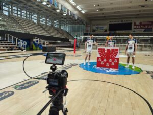 Kamera mit drei Spielern von Trentino Volley im Hintergrund und dem Sparkasse-Logo im Vordergrund