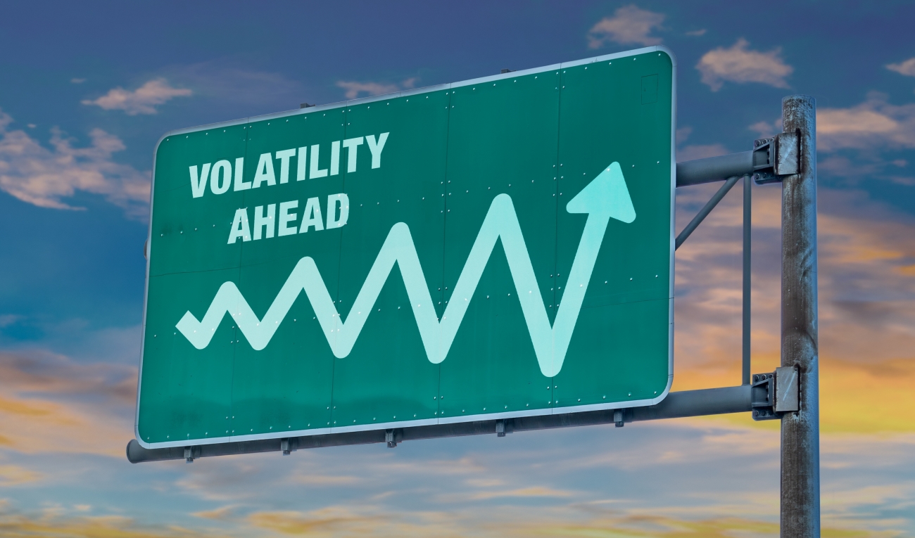 Grünes Autobahnschild mit der Aufschrift „Volatility ahead“ und einem winkenden Pfeil