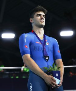 Matteo Bianchi in einem blauen italienischen Radanzug mit einem Topf mit einer Pflanze darin auf dem Rücken.