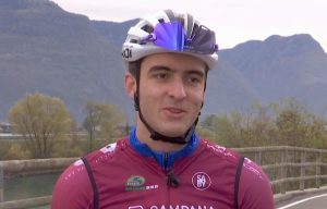Matteo Bianchi mit weißem Fahrradhelm, Rennbrille und burgunderrotem Overall